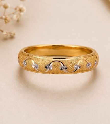 A 21K gold band ring with a matte textured finish and delicate silver swirls, no gemstones